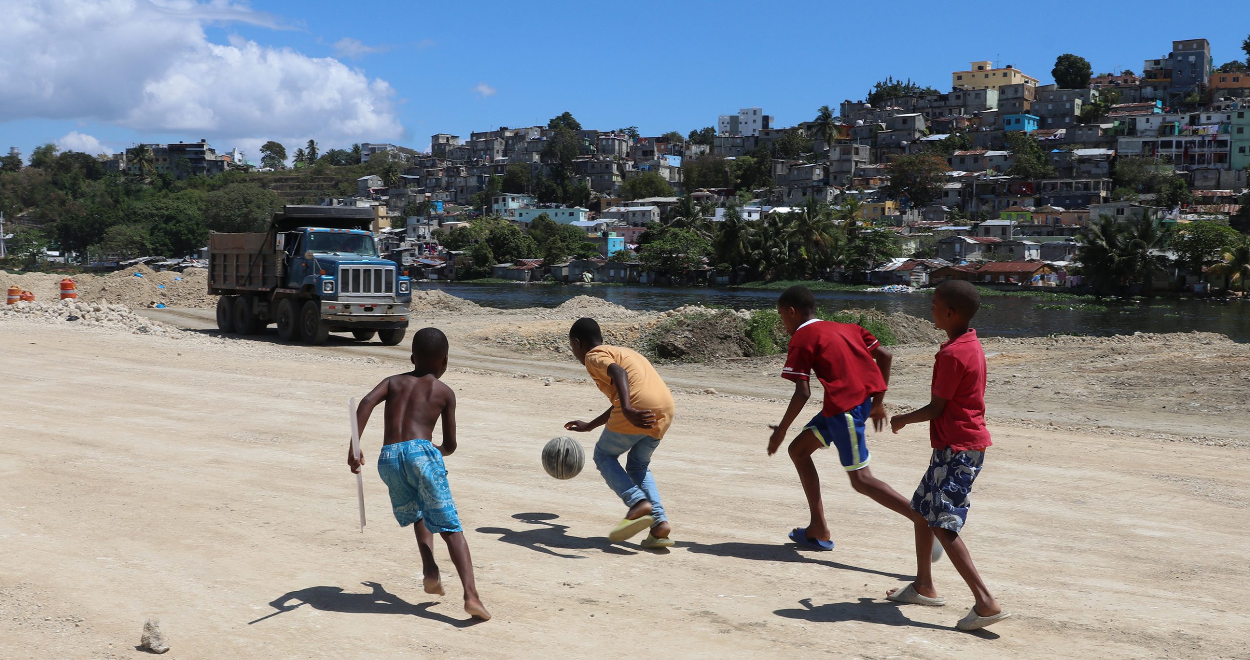 Kids play basketball on the site where the government is building a road in Domingo Savio on March 3, 2023. The thousands of homes that once stood along this stretch of the Ozama River were torn down as part of an infrastructure project. (Photo by Caitlin Thompson/Cronkite Borderlands Project)
