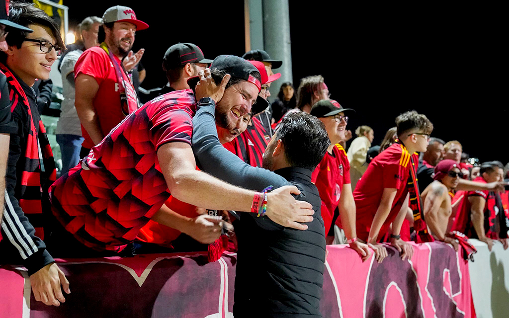 Kieran Thompson, one of the supporters from Los Bandidos, celebrates with coach Juan Guerra after the team’s recent playoff victory against Orange County. (Photo courtesy of Phoenix Rising FC)