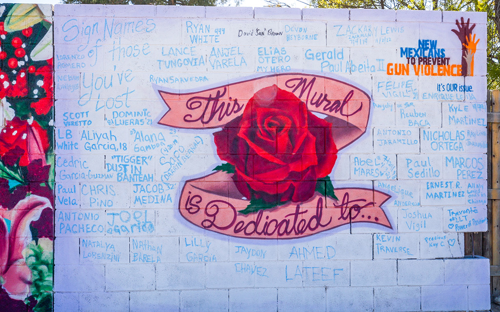 A section of the mural from New Mexicans to Prevent Gun Violence is covered with the names of those lost to gun violence. People attending the unveiling of the mural outside San Pedro Library in Albuquerque on Nov. 4, 2023, wrote the names on the wall. (Photo by John Leos/Cronkite News)