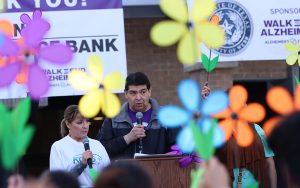 Jerry Garza, a co-host of the event and news director for KGNS-TV, instructing the crowd to raise their flowers before the start of the annual Walk to End Alzheimer’s in Laredo, Texas, on Nov. 4. (Photo by Angelina Steel/Cronkite News)