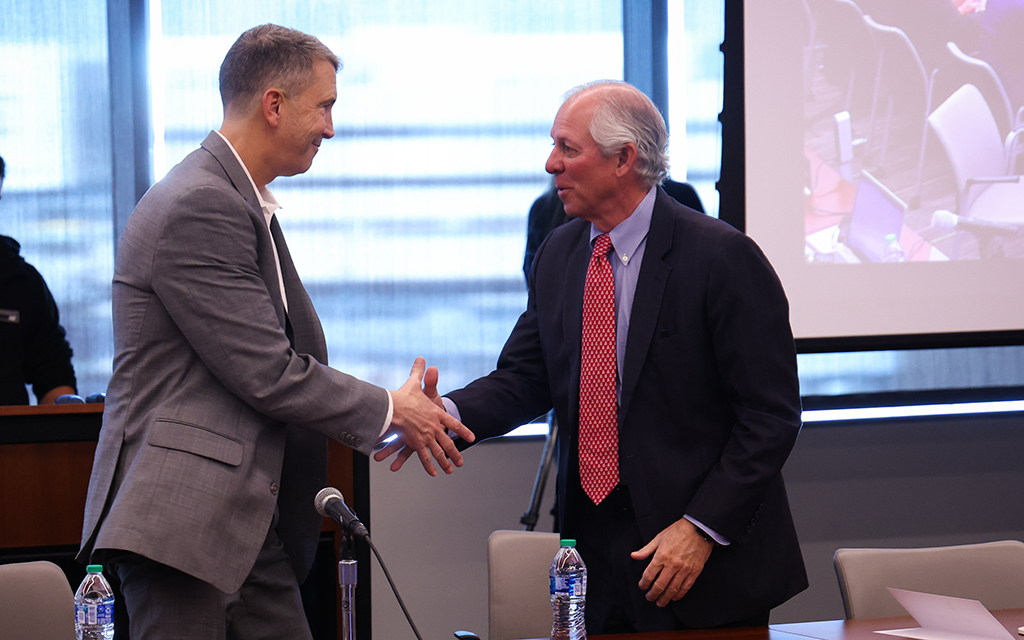 University of Arizona president Robert Robbins, right, shakes hands with the newly appointed head coach, Brent Brennan, following the Arizona Board of Regents’ approval of Brennan’s contract. (Photo by Bennett Silvyn/Cronkite News)