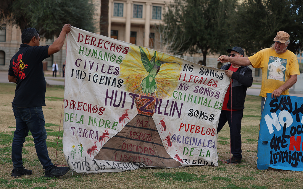 From left, Cipranio González, Raul Cordero and Rob McElwain put a sign up in protest of bills critics say are anti-immigrant at Arizona State Capitol on Feb. 1, 2024. (Photo by Marnie Jordan/Cronkite News)