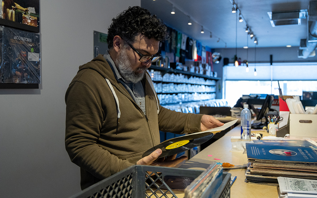 Dario Miranda, who works for Stinkweeds Records, inspects a vinyl for scratches or imperfections. Photo taken in Phoenix on Jan. 22, 2024. (Photo by Emily Mai/Cronkite News)
