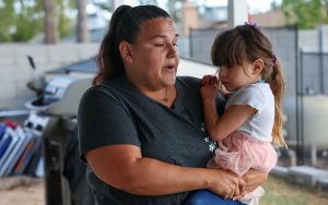 Brandi Stoll holds her 4-year-old daughter, Alizah Aguilar, on Feb. 21, 2024, at their home in Phoenix while discussing the family’s decision to install a fence around their pool. Alizah nearly drowned in the pool more than two years ago. (Photo by Harris Hicks/Cronkite News)