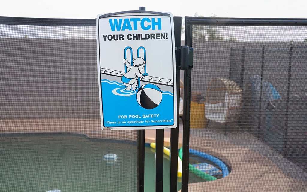 A "Watch your children!" sign hangs on Sam Aguilar and Brandi Stoll’s pool fence on Feb. 21, 2024, in Phoenix. (Photo by Harris Hicks/Cronkite News)