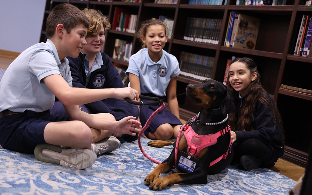 Great Hearts Archway Veritas Academy Director of Operations Ami Hosack, left, lets Jack Cooling, an 11-year-old fifth grader, feed therapy dog Karma at the school on Jan. 25, 2024. (Photo by Marnie Jordan/Cronkite News)