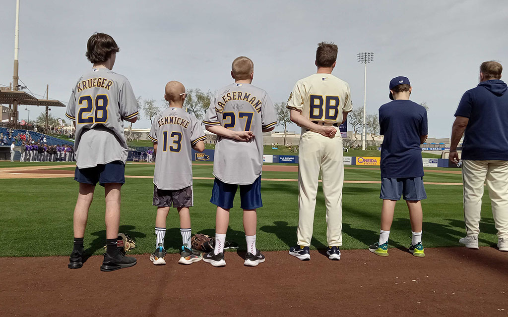 Brandon Krueger, left to right, Malakai Kaesermann and Evan Rennicke stand for the national anthem after throwing out the first pitch at American Family Fields of Phoenix. (Photo by Jesse Brawders/Cronkite News)