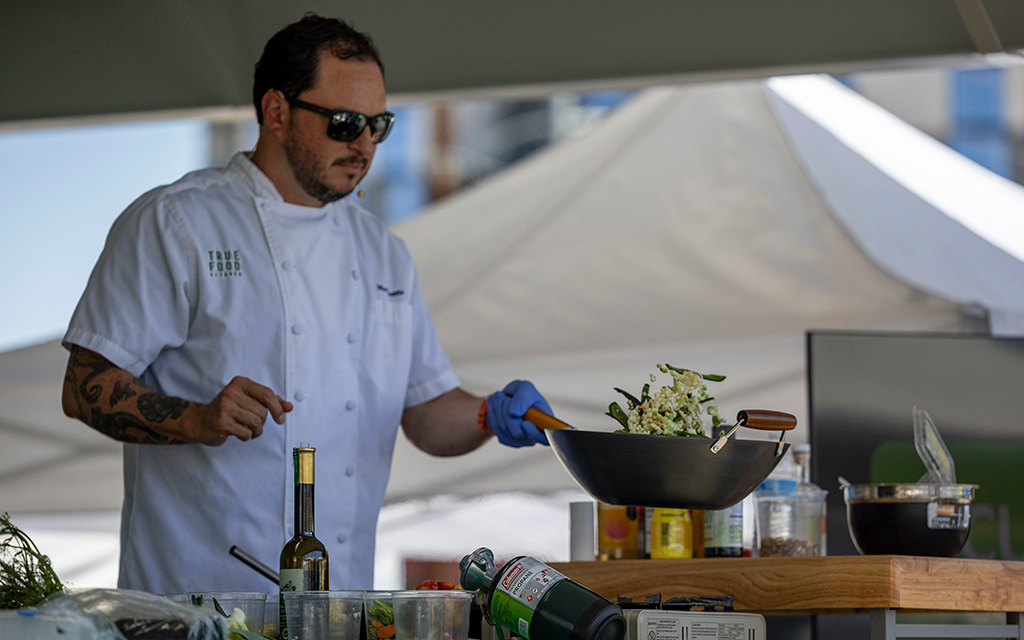 Chef Matthew Padilla, True Food Kitchen’s senior vice president of culinary, cooks stir fry at the Health & Wellness Phoestival in downtown Phoenix on April 13, 2024. (Photo by Sam Ballesteros/Cronkite News)