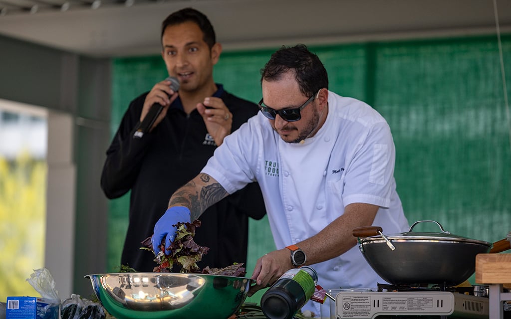 Chef Matthew Padilla, True Food Kitchen’s senior vice president of culinary, mixes a salad with ingredients from the Downtown Phoenix Farmers Market as Dr. Shad Marvasti explains the health benefits of different ingredients at the Health & Wellness Phoestival on April 13, 2024. (Photo by Sam Ballesteros/Cronkite News)