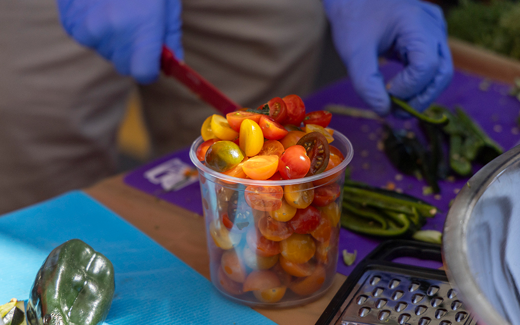 University of Arizona Culinary Medicine students chop up tomatoes for chef Matthew Padilla’s cooking demonstration at the Health & Wellness Phoestival in Phoenix on April 13, 2024. (Photo by Sam Ballesteros/Cronkite News)