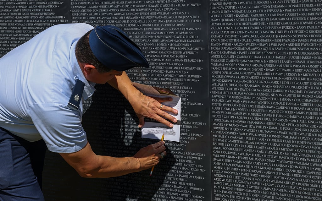 Retired U.S. Air Force Lt. Col. Roel Zamora shades the name of a loved one onto a piece of paper at The Wall That Heals exhibit at Lake Pleasant in Peoria on April 11, 2024. (Photo by Kayla Mae Jackson/Cronkite News)