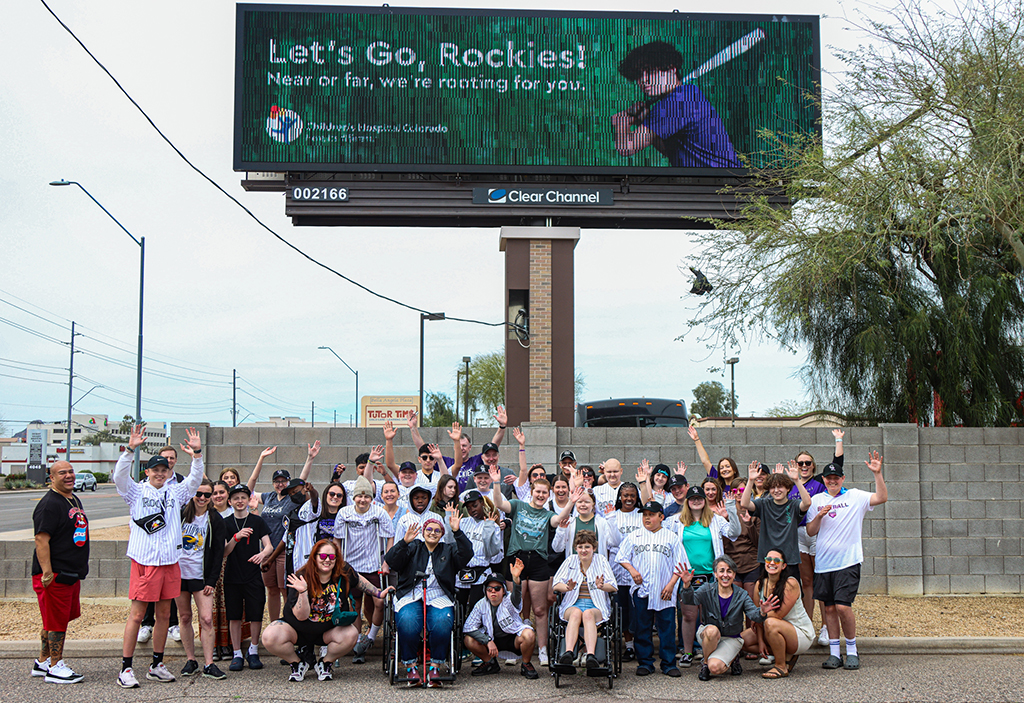 Patients from the Children’s Hospital Colorado cancer division pose in front a billboard that represents their program, which helped them meet Colorado Rockies players during spring training. (Photo by Spencer Barnes/Cronkite News)
