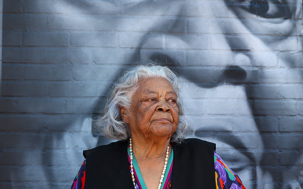 Elizabeth White, 101, stands in front of the Legacy Project mural painted at Eastlake Park Community Center in Phoenix after the unveiling of the NCAA Men’s Final Four Legacy Project, which refurbished indoor and outdoor basketball courts and upgraded other amenities at the center. (Photo by Kayla Mae Jackson/Cronkite News)