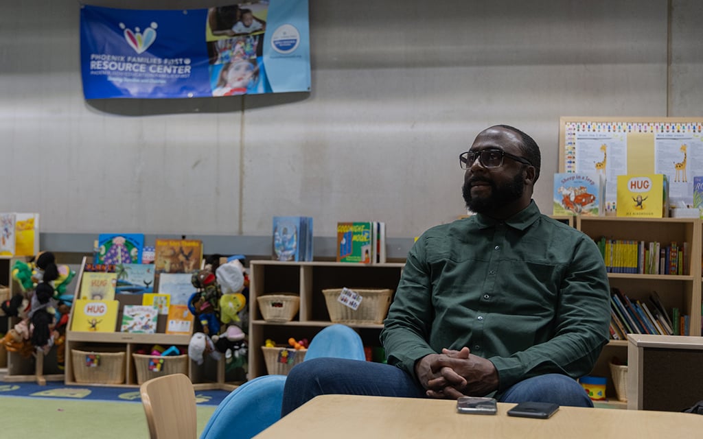 Lord Washington, a father support specialist for Dad Together, sits at one of the children’s tables in the Phoenix Families First Resource Center in the Burton Barr Central Library. Washington is a Dad Together alum and now leads classes. Photo taken in Phoenix on April 8, 2024. (Photo by Emily Mai/Cronkite News)
