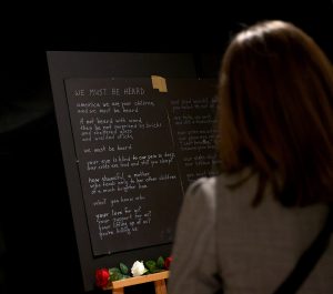 A patron reads the poem “We Must Be Heard” during opening night of the “Twin Flames” exhibit at the ASU Art Museum in Tempe on Feb. 2, 2024. The exhibit puts on display offerings by mourners and protesters during the protests in Minneapolis after the death of George Floyd. (Photo by Kevinjonah Paguio/Cronkite News)