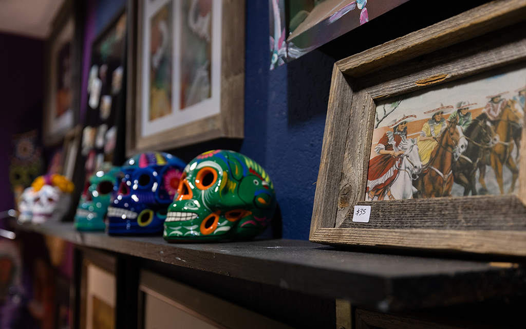 A display of art in different media at the Arizona Latino Arts & Cultural Center in downtown Phoenix, ranging from traditional oil paintings of charrerías, a Mexican equestrian sport, to calaveras, traditional Mexican skull sculptures. (Photo by <a href="https://cronkitenews.azpbs.org/people/david-ulloa-jr/" rel="noopener" target="_blank">David Ulloa Jr.</a>/Cronkite News)