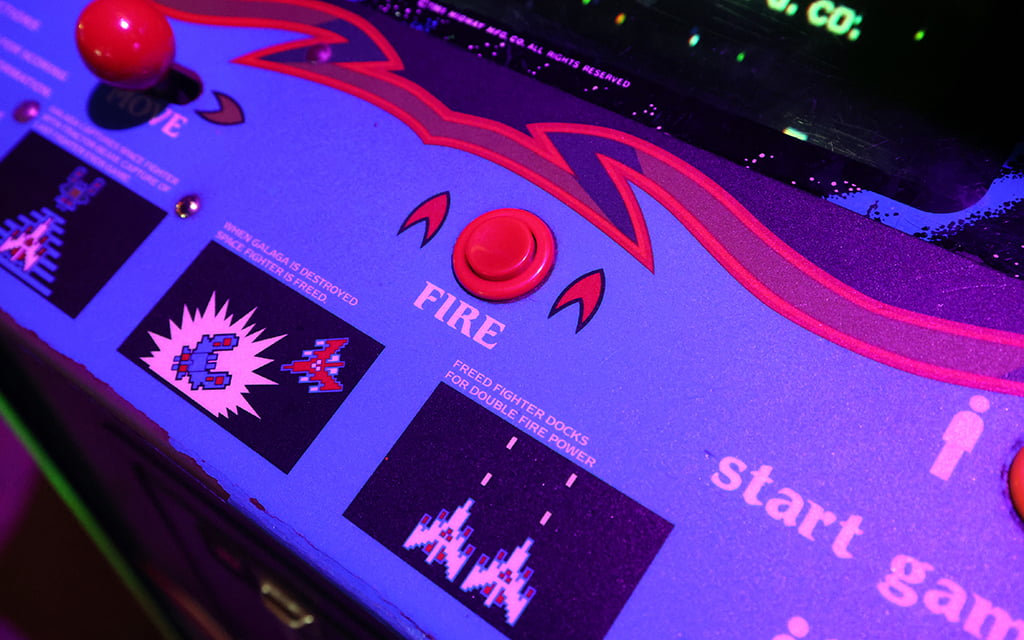 A close-up of the Galaga arcade machine at Cobra shows its control panel and highlights the "Fire" button and gameplay instructions for players. Photo taken on June 26, 2024. (Photo by Stella Subasic/Cronkite News)