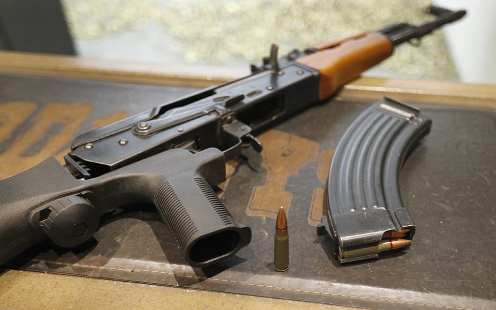 A 7.62x39 mm round sits next to a 30-round magazine and an AK-47 with a bump stock installed. The bump stock is a device that allows a semi-automatic to fire at a rapid rate much like a fully automatic gun. (Photo by George Frey/Getty Images)