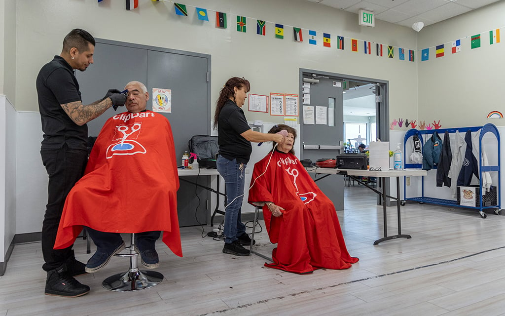 David Rodriguez cuts Daniel Holguin’s hair, left, while Moraima Robledo gives Maria Castillo, right, a haircut at the Glendale Community Center on April 8, 2024. (Photo by Sam Ballesteros/Cronkite News)