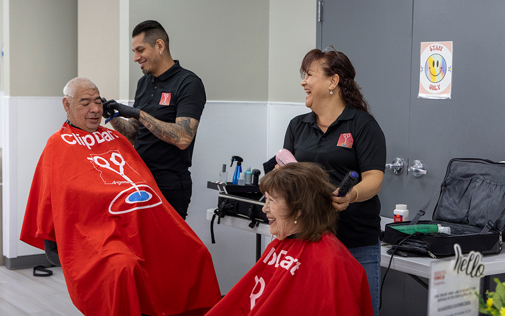 Daniel Holguin, left, and Maria Castillo (right) sit for their haircuts at the Glendale Community Center on April 8, 2024. (Photo by Sam Ballesteros/Cronkite News)