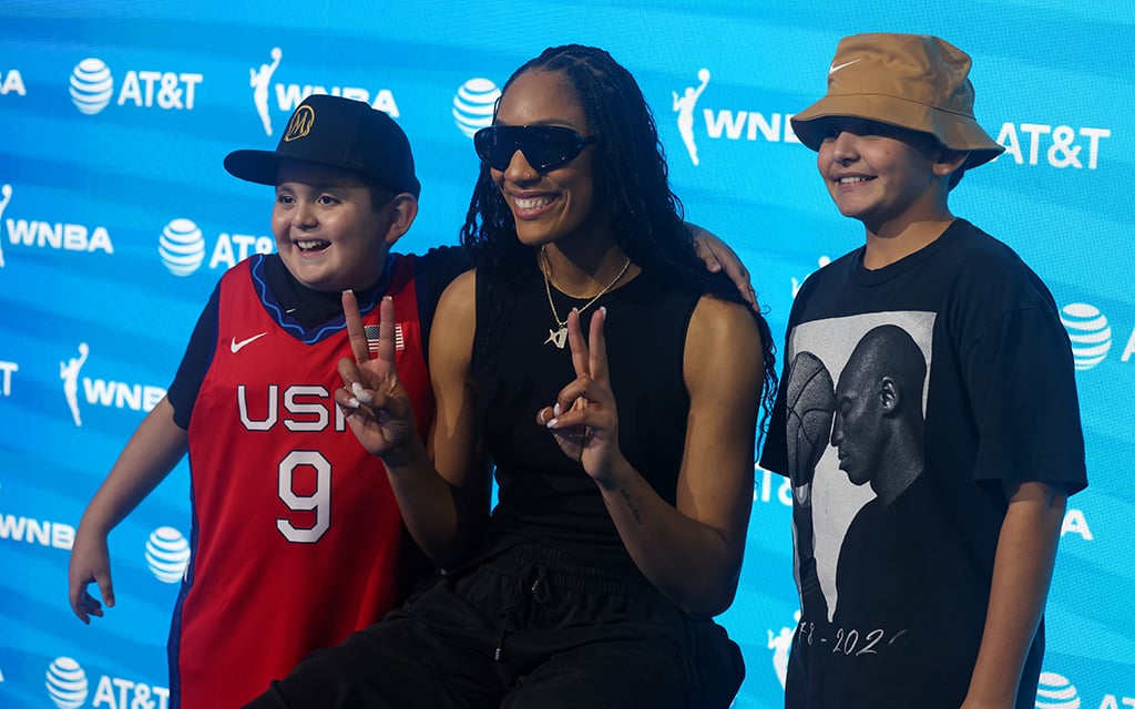 A'ja Wilson, middle, shares a heartfelt moment with a young fan wearing her Team USA jersey at the WNBA Live fan experience in Phoenix. (Photo by Grace Hand/Cronkite News)