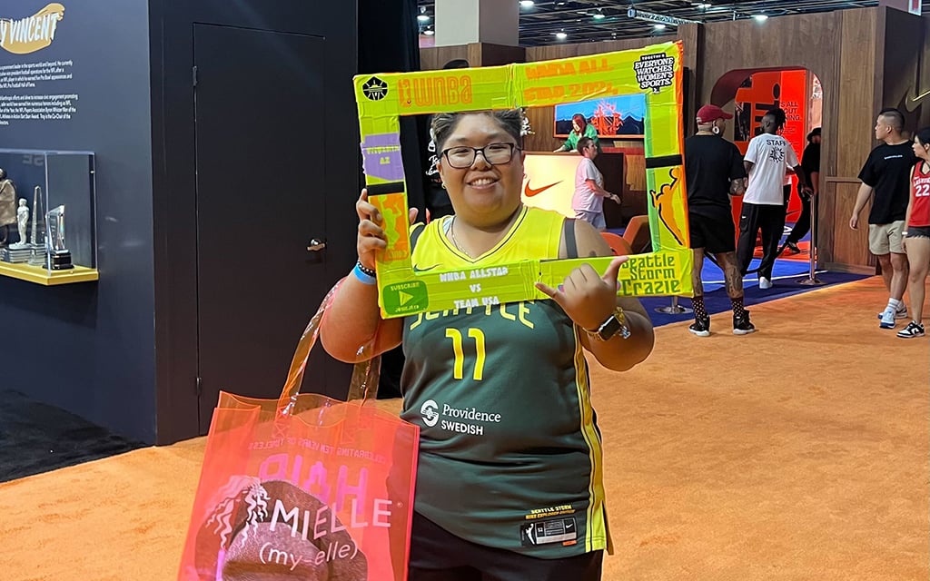 Josie Dumlao, known as @stormcraziefanframe on Instagram, shows off her iconic neon green sign frame at Friday's WNBA Live event in downtown Phoenix. (Photo by Mateo Arenas/Cronkite News)