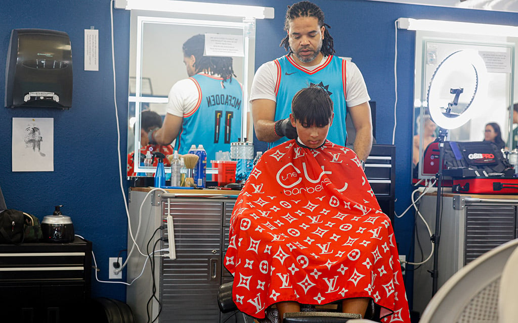 Barber Brandon McFadden gives a complimentary haircut to Vance Robinson at ASU running back DeCarlos Brooks' Cutback Giveback Haircut Event. (Photo by Shirell Washington/Cronkite News)