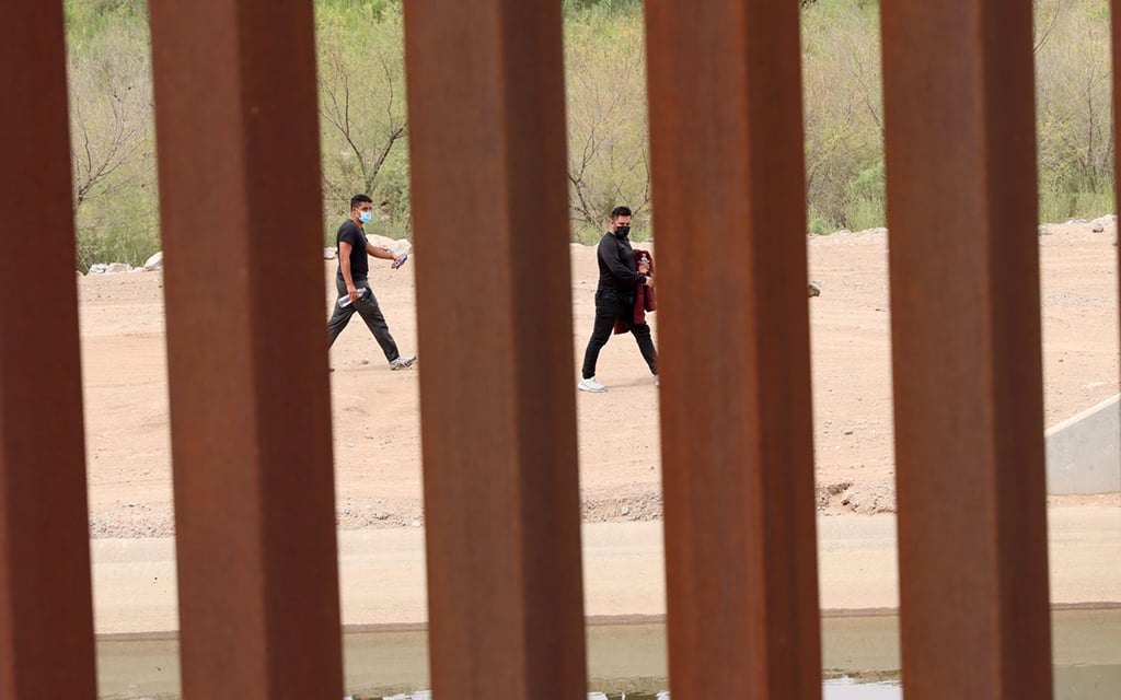 Two people walk along the Mexican side of the border fence near Yuma on Sept. 8, 2022. (File photo by Alexia Faith/Cronkite News)