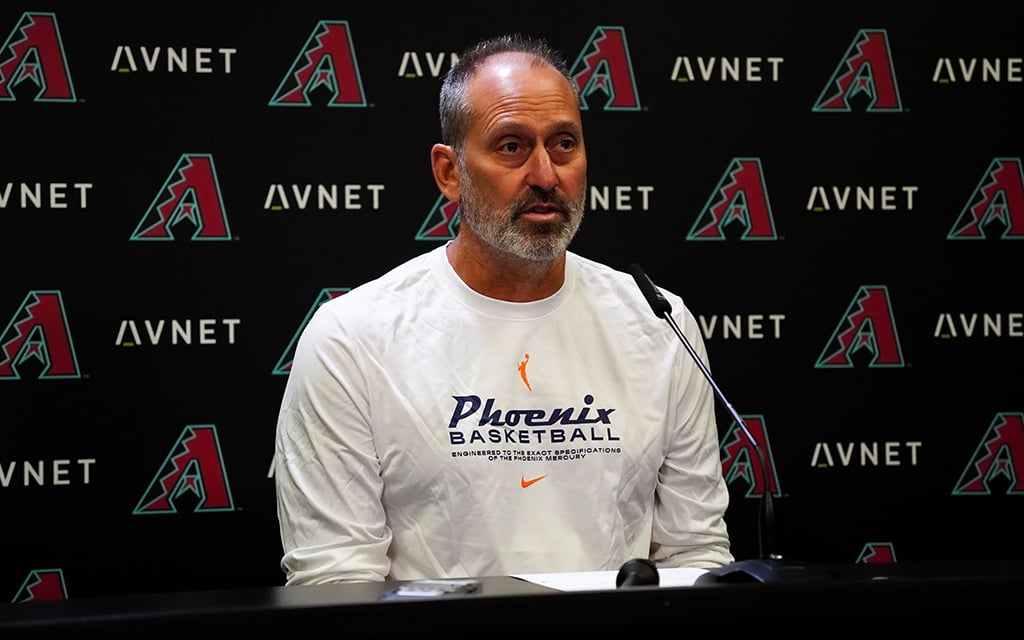 Manager Torey Lovullo speaking at a press conference with an Arizona Diamondbacks backdrop.