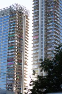 Two abandoned structures with balconies covered in various colorful graffiti art, tree partially visible on the right.