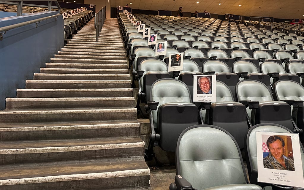 Staircase leading through rows of empty stadium seats, with photographs and names of 9/11 victims attached to some seats.