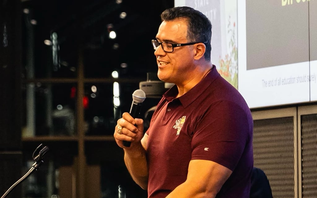 Juan Roque speaking into a microphone at an indoor event.