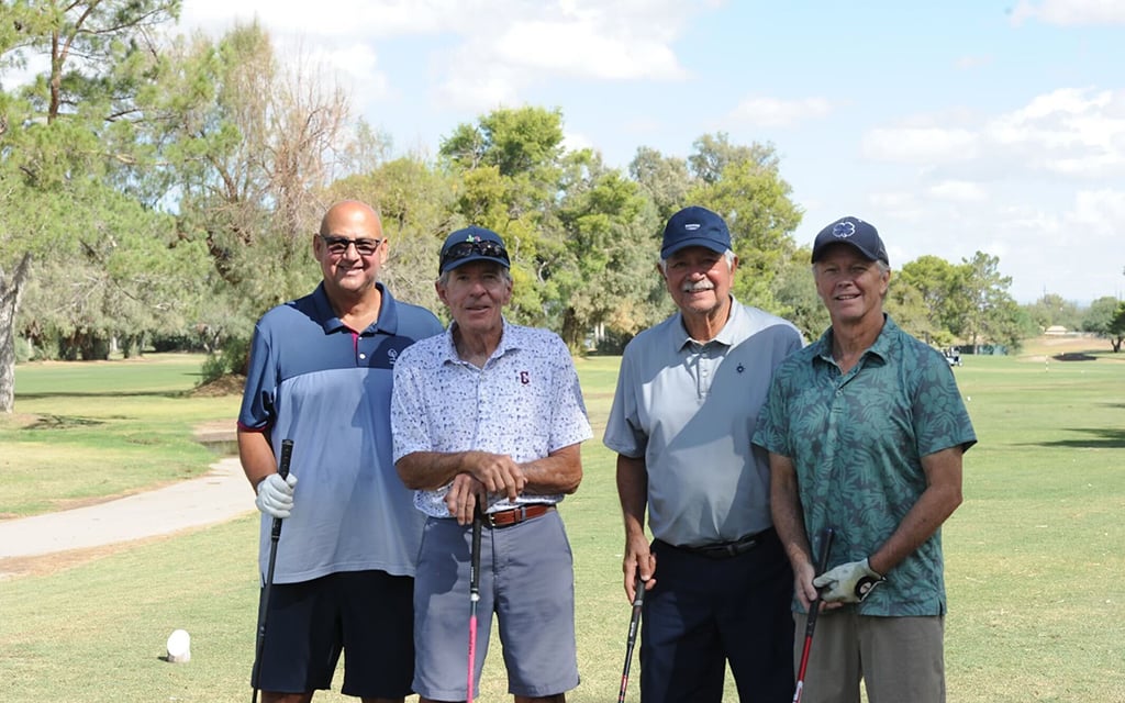 Terry Francona and three others standing together on a golf course holding golf clubs, smiling at the camera.