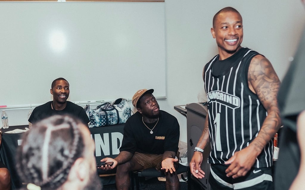 Jamal Crawford, Nate Robinson and Isaiah Thomas in a casual indoor setting, with one standing and smiling in the foreground and two seated behind him.