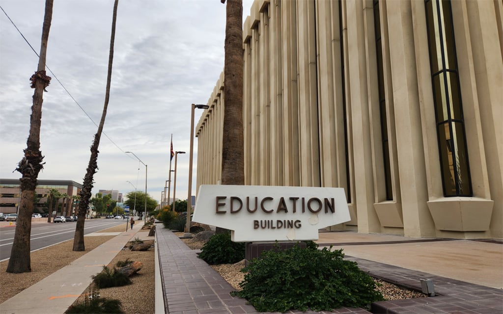 Education Building sign next to a modern beige structure with palm trees and a walkway.