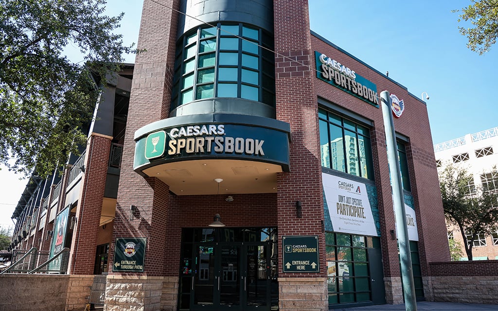 Brick building in Phoenix, AZ with large glass windows and "Caesars Sportsbook" signs above and beside the entrance.