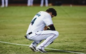 Baseball player in a white uniform with number "44" crouching on a field.