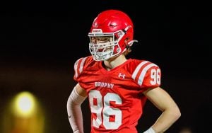 Bastian Vanden Bosch, in a red uniform and helmet with "Brophy" and number "96" on the jersey, standing with hands on hips on a field at night.