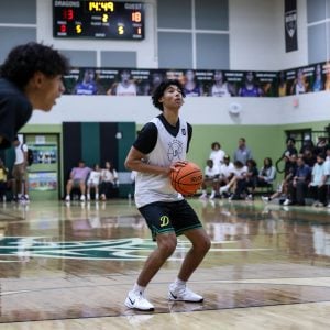 Basketball player in a gym preparing to take a free throw with spectators in the background.