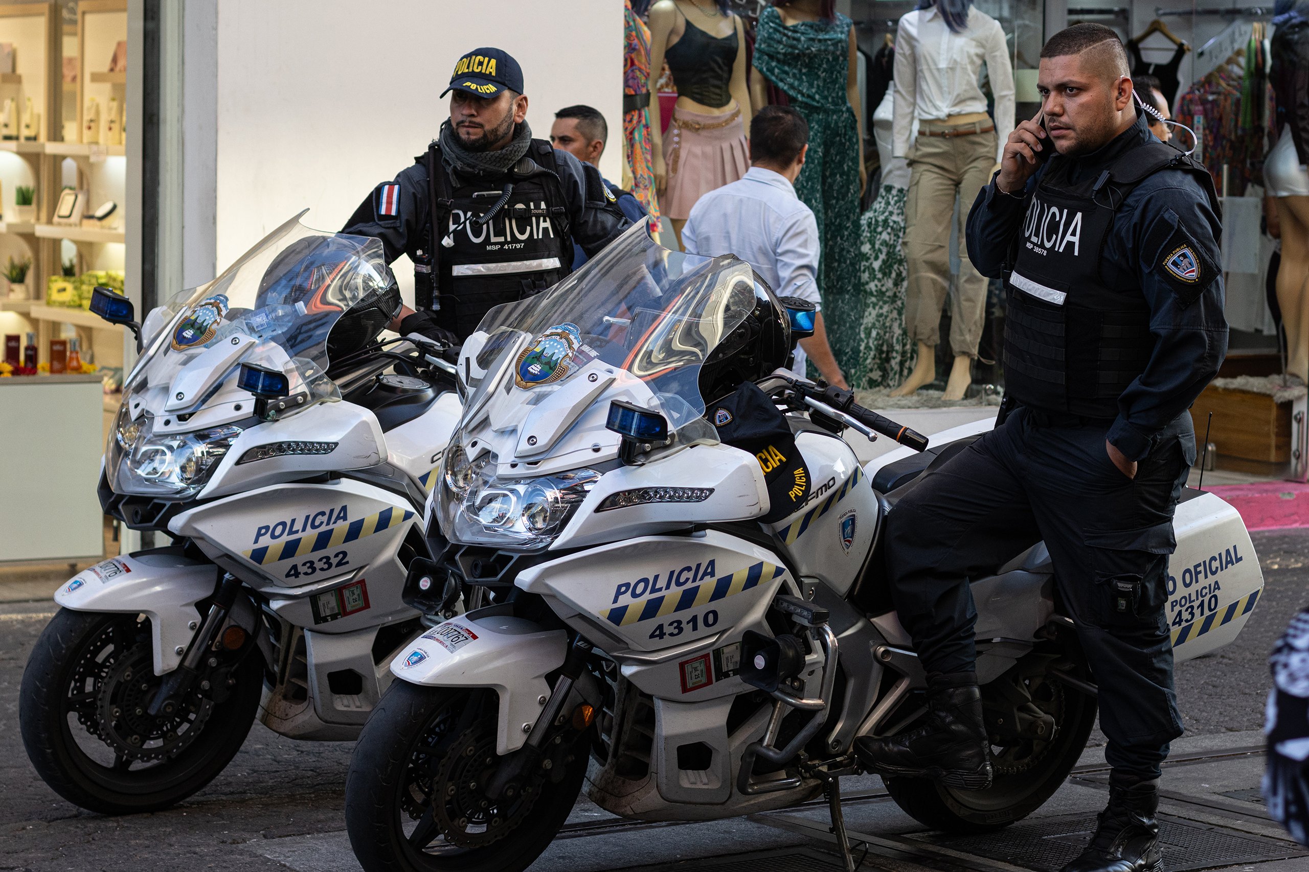 Two Costa Rican police officers watch passersby on Central Avenue in downtown San Jose, Costa Rica, on March 1, 2024. According to Costa Rica’s Judicial Investigation agency (OIJ), there were over 900 homicides in 2023—the most violent year in the country’s history. Officials primarily attributed them to narcotrafficking groups. (Photo by Carly Stoenner/Cronkite Borderlands Project)
