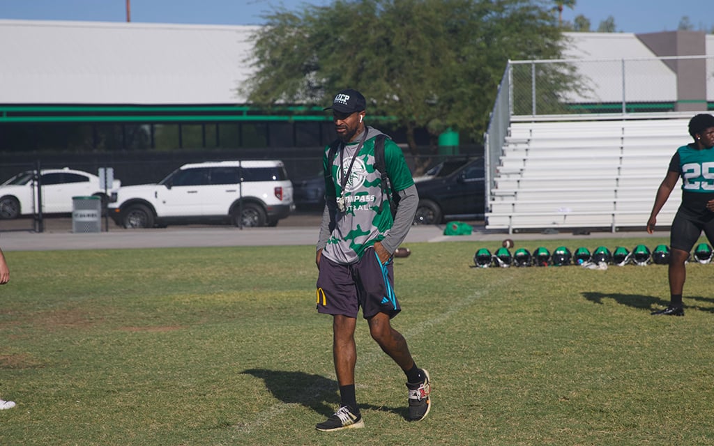 Jaelen Strong walking on a football field with helmets lined up and a player standing nearby.