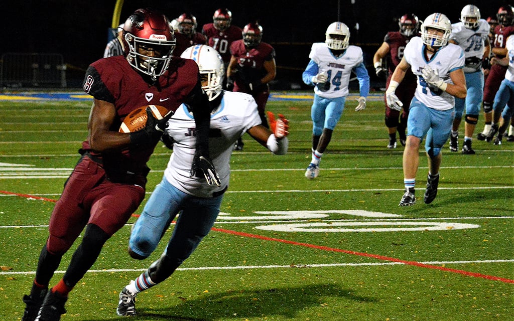 Marvin Harrison Jr. in a maroon uniform runs with the ball, pursued by a player in white and blue.