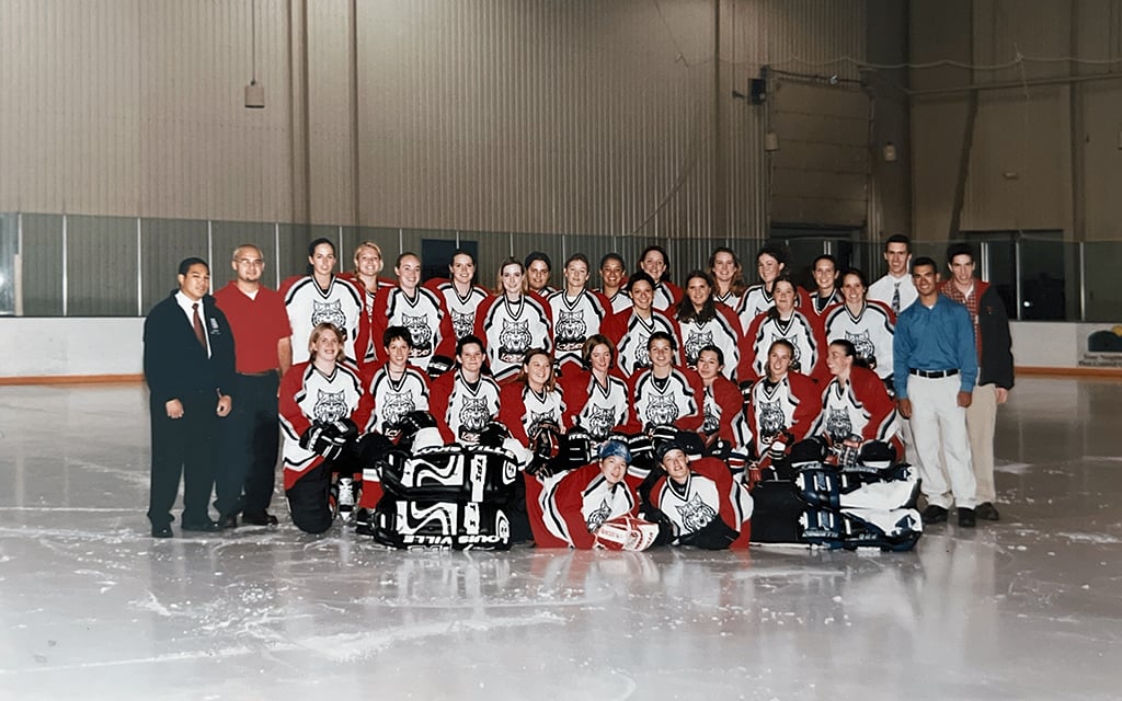 The University of Arizona Icers women's ice hockey team in red, blue, and white uniforms posing on an indoor ice rink.