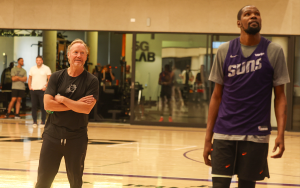 Coach looks up and works with player at Suns practice facility