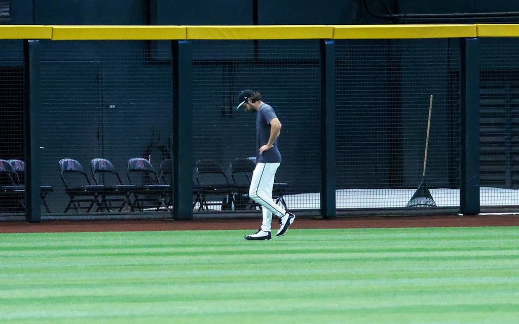 Zac Gallen walking on a baseball field near the left outfield wall with the number "330" and folding chairs behind fencing.