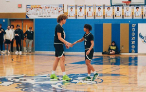 Two basketball players high five at middle court