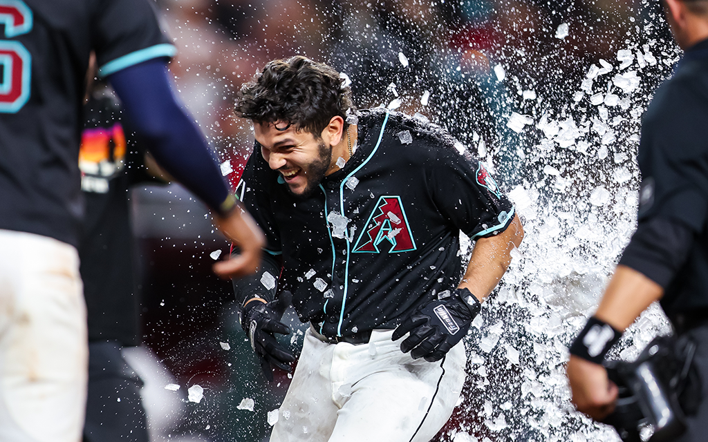 Baseball player in black jersey celebrating, surrounded by exploding ice fragments.