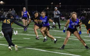 Xiamara Drummer, GCU flag football player, running with the ball, surrounded by teammates and opponents.