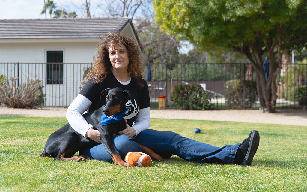 Lisa Futo sitting on a lawn with a Felicity in front of her and a house in the background.